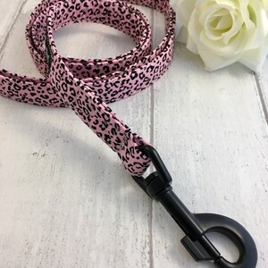 May include: Pink and black leopard print dog leash with a black metal clip.