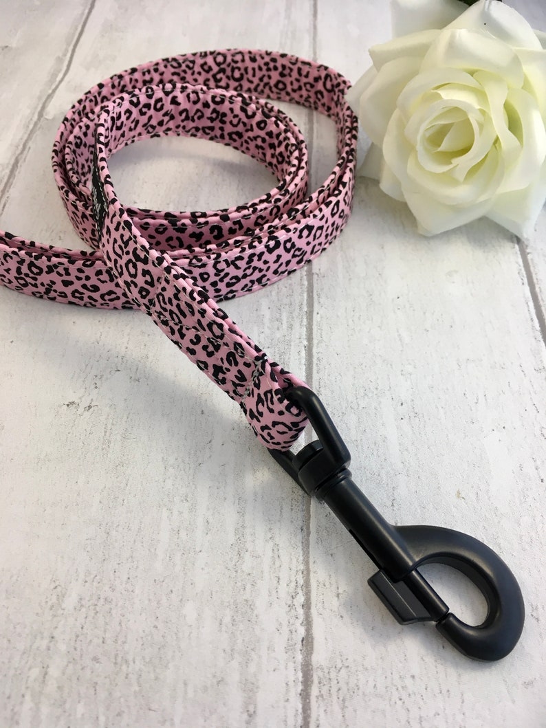 May include: Pink and black leopard print dog leash with a black metal clip.