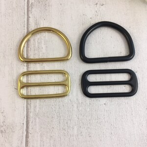 May include: Two sets of metal D-rings and slider buckles. One set is gold and the other is black.