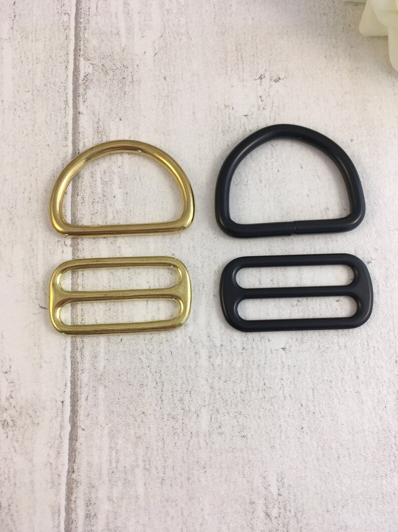 May include: Two sets of metal D-rings and slider buckles. One set is gold and the other is black.