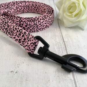May include: Pink and black leopard print dog leash with a black metal clip.