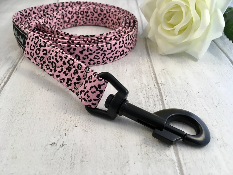 May include: Pink and black leopard print dog leash with a black metal clip.