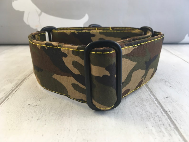 May include: A camouflage dog collar with black metal hardware and yellow stitching.