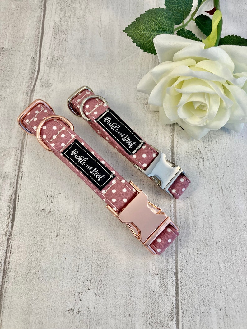 May include: Two dog collars in a mauve polka dot design. One has rose gold hardware, the other silver. Each collar features a black label with the white text "Pickle and Boot".