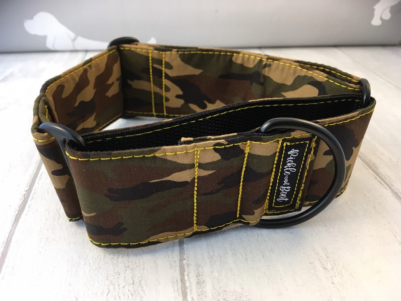 May include: A camouflage dog collar with yellow stitching and a black metal buckle. The collar has the text "Ruff &  Woof" embroidered on it.