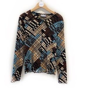 May include: A long-sleeved, brown, blue and beige patterned shirt with a button closure. The shirt is made of a sheer, mesh fabric and has a scalloped hem.