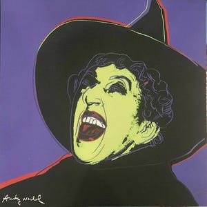 May include: Pop art print of a woman with green skin, wearing a black witch hat, and screaming. The artwork features bold colors, including purple, black, red, and green. The artist's signature, "Andy Warhol," is in the bottom left corner.