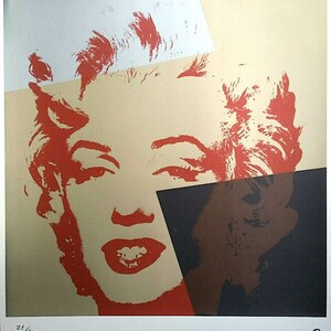 May include: A pop art print featuring a stylized portrait of Marilyn Monroe. The image uses bold red, beige, and black color blocks to depict her face. The print is numbered 21/100 and signed by the artist.