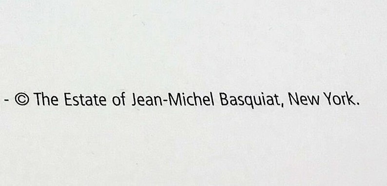 May include: Text on a white background reads: "- &copy; The Estate of Jean-Michel Basquiat, New York." The text is in a simple, sans-serif font. The image is a close-up shot.