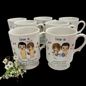 May include: A collection of white ceramic mugs featuring the Love Is cartoon characters. Each mug displays a unique illustration with text such as love is... letting him have the last word sometime and love is... fixing her breakfast in the morning.