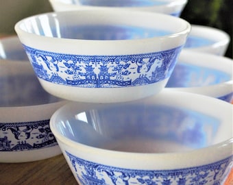 May include: Stack of four white ceramic bowls with a blue and white willow pattern. The bowls are nested inside each other.