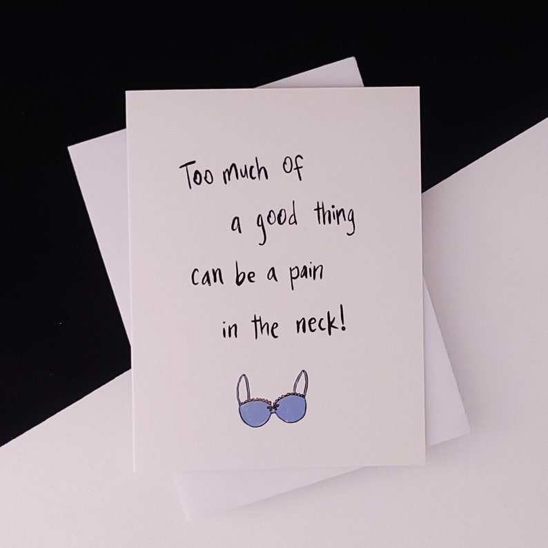 May include: A white card with black handwritten text that reads "Too much of a good thing can be a pain in the neck!" and a blue bra illustration.