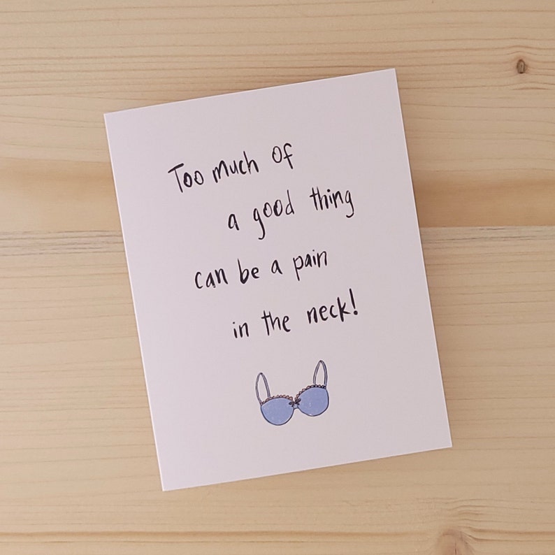 May include: A white card with black handwritten text that reads "Too much of a good thing can be a pain in the neck!" and a blue bra illustration.