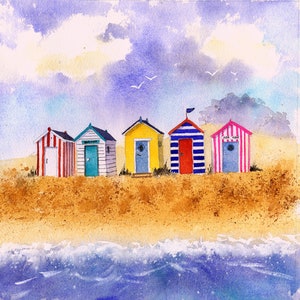 Op de afbeelding: Een aquarel van vijf kleurrijke strandhuisjes op een zandstrand met blauwe oceaan golven op de voorgrond. De huisjes zijn geschilderd in rood, wit, blauw, geel en roze.