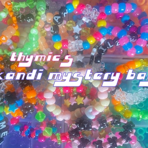 Può includere: Primo piano di una varietà di braccialetti kandi colorati. I braccialetti sono fatti di perline di plastica e presentano diverse forme, lettere e disegni. Il testo "thymic's kandi mystery bag" è visibile al centro dell'immagine.