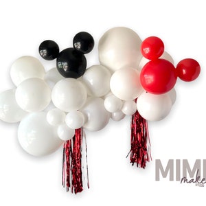 May include: A balloon garland with white, black, and red balloons. The garland features two Mickey Mouse ears, one black and one red. The garland is decorated with red and silver streamers.
