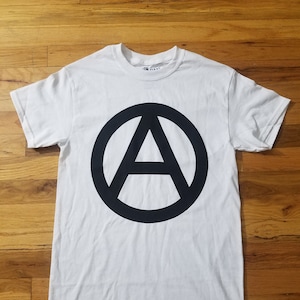 Peut inclure: T-shirt blanc avec un symbole d'anarchie noir imprimé sur le devant.