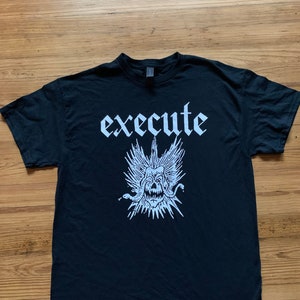 Puede incluir: Camiseta negra con un estampado gráfico blanco de una calavera con alas y serpientes, y la palabra "execute" en una fuente gótica.