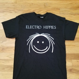 May include: Black t-shirt with white text that reads "Electro Hippies" and a white smiley face with messy hair.