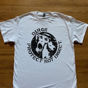 May include: White t-shirt with a black and white graphic print of two dogs with the text "Durge Protect Not Disect."