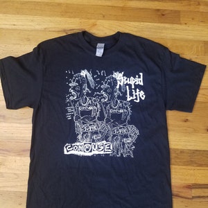 May include: Black t-shirt with a white graphic print of two cartoon figures with the text "Stupid Life" and "Comouse" on the front.