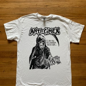 May include: White t-shirt with a black and white graphic print of a skeleton holding money. The text "ANTI-CIMEX" and "I'LL BUY ALL THE URANIUM YOU'VE GOT..." is printed on the shirt.