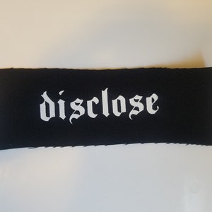 May include: Black fabric patch with white text that reads "disclose" in a gothic font.