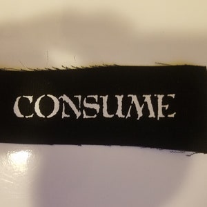 May include: Black fabric patch with white text that reads "CONSUME".