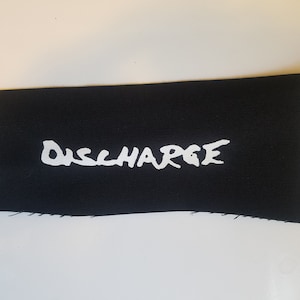 May include: Black fabric patch with white lettering that reads "DISCHARGE".