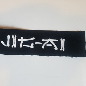 May include: A black fabric patch with white lettering that reads "JITA-XI".