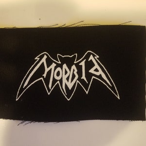 May include: A black fabric patch with a white bat design and the word "MORBID" written in a stylised font.