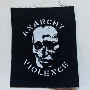 Könnte beinhalten: Schwarzer Stoff-Patch mit weißem Text und einer Totenkopfgrafik. Der Text lautet "ANARCHY VIOLENCE".