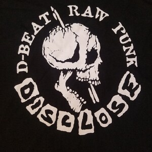 May include: Black t-shirt with a white circle graphic. The graphic features a skull with a needle going through its head. The text "D-BEAT RAW FUNK DISCLOSE" is written around the skull.