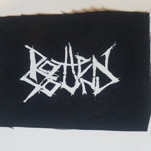 Puede incluir: Parche de la banda "Rotten Sound" en blanco sobre un fondo de tela negro.