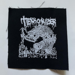 May include: Black and white embroidered patch with the text "Terrorizer" in a stylized font. The patch features a graphic of a creature with sharp teeth and claws.