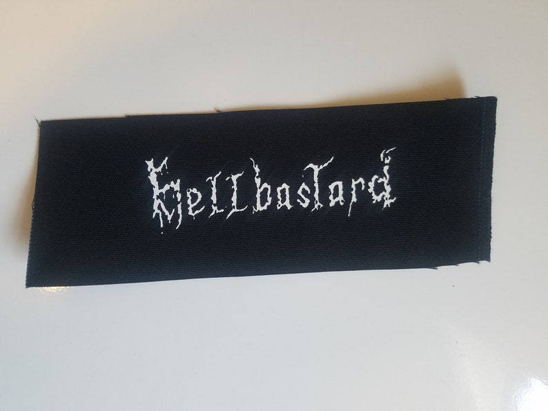 May include: Black fabric patch with white embroidered text that reads "Hellbastard".
