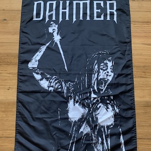 Puede incluir: Bandera en blanco y negro con la palabra "DAHMER" impresa en grandes letras blancas en la parte superior. La bandera presenta una imagen gráfica de una persona sosteniendo un cuchillo, con un diseño blanco sobre negro desgastado.