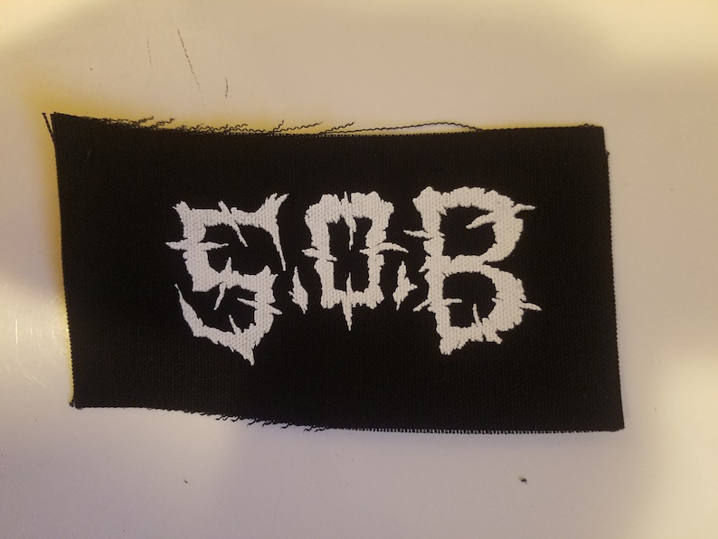 May include: Black fabric patch with white embroidered lettering that reads "SLAB".