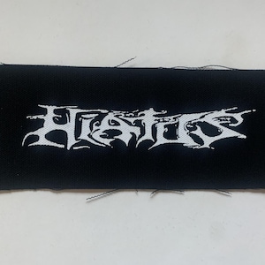 Puede incluir: Parche tejido negro con el texto blanco "HATE" en una fuente estilizada.