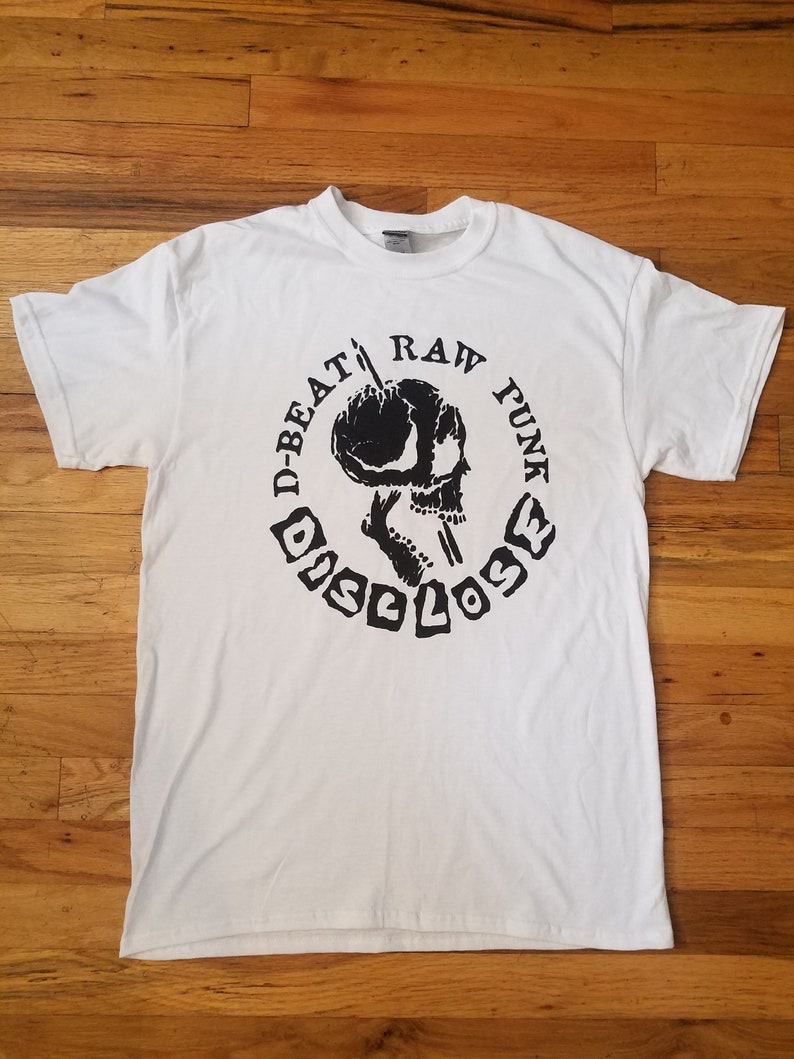 May include: White t-shirt with a black and white graphic print of a skull with a microphone in its mouth. The text around the skull reads "D-Beat Raw Punk Disclose".