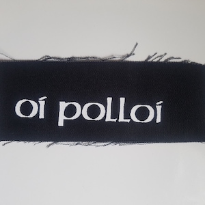 May include: Black fabric patch with white embroidered text that reads "oi polloi".