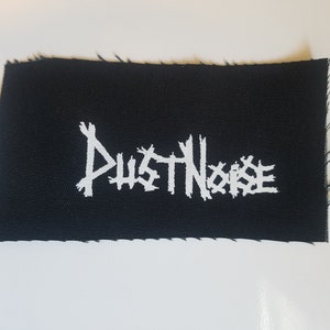 May include: Black fabric patch with white embroidered text that reads "DUST NOISE".