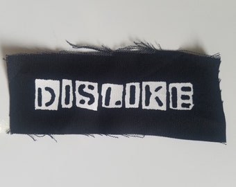 Puede incluir: Parche de tela negro con letras blancas que dicen "DISLIKE" en letras de bloque.