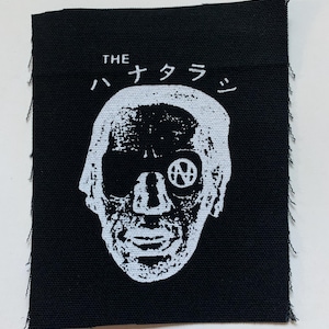 May include: Black and white embroidered patch with a skull-like face and the text "THE ハナタラジ" in white.
