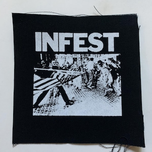 May include: Black and white patch with the word "INFEST" in white letters and a black and white image of a group of people in the background.