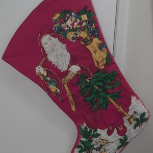 May include: A red Christmas stocking with a white Santa Claus holding a bag of toys. The stocking is decorated with holly and a green tree.