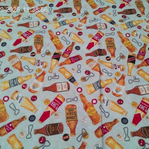 May include: Fabric with a repeating pattern of beer bottles, bottle openers, and bottle caps in shades of brown, red, and yellow on a light blue background. The bottles have various labels, including "Pilsner" and "German Oldale".