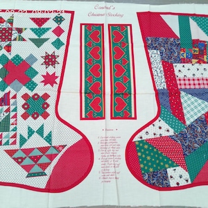 Pode incluir: Um painel de tecido para costurar duas meias de Natal, com o texto "Conrad's Christmas Stocking" e instruções impressas. O design inclui padrões estilo patchwork em vermelho, verde e branco, com motivos de corações e estrelas.