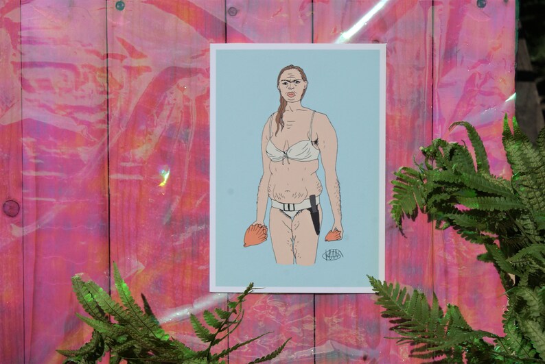 May include: A print featuring a cartoon illustration of a person in a white bikini and holding a knife and an orange object. The artwork is set against a light blue background and framed in white.
