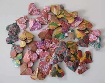 May include: A collection of origami hearts in various colors and patterns, including red, orange, yellow, green, blue, and purple. The hearts are folded from paper and have a variety of designs, including floral, geometric, and abstract.